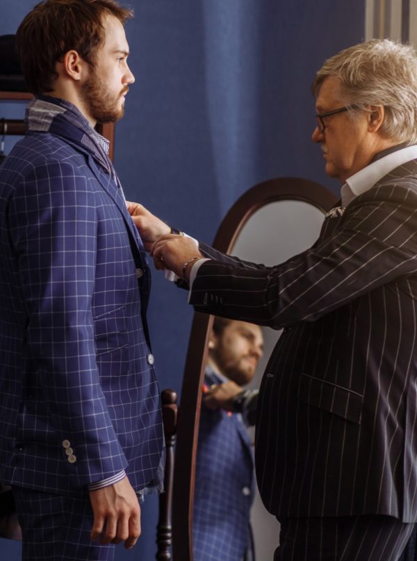 Handsome young groove male trying on classical mans suit getting ready to wedding ceremony